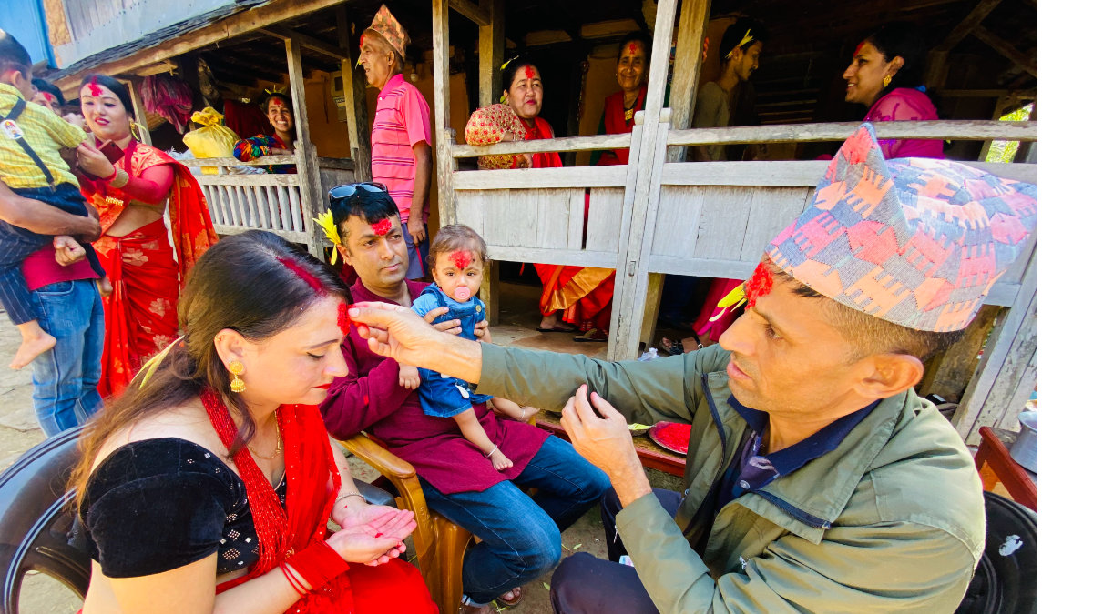 Elder placing tika and jamara on a younger family member’s forehead